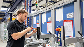 Mann in Arbeitskleidung in einer Werkshalle