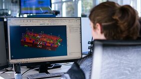 Junge Frau von hinten zu sehen arbeitet am Computer an einem Rendering