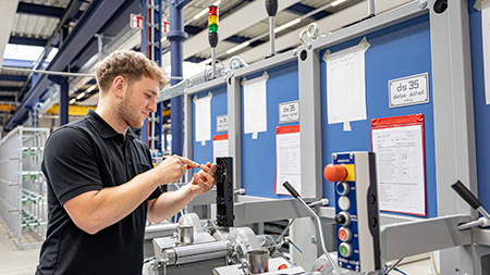 Mann in Arbeitskleidung in einer Werkshalle