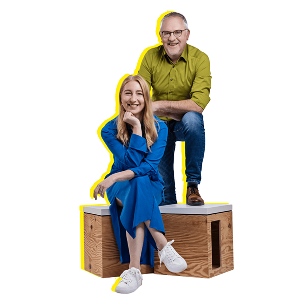 Eine Mann und eine Frau auf Holzhockern vor weißem Hintergrund