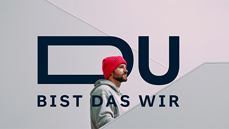 Junger Mann mit roter Mütze vor Wand mit Schriftzug